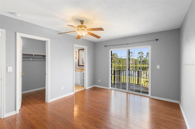 unfurnished bedroom with access to exterior, ceiling fan, light hardwood / wood-style flooring, a walk in closet, and a closet