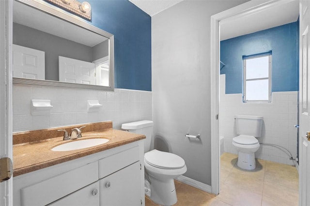 bathroom featuring tile patterned flooring, vanity, toilet, and tile walls