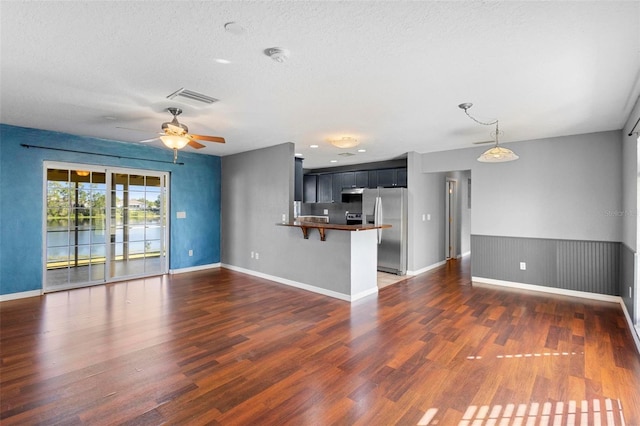 unfurnished living room with a textured ceiling, ceiling fan, and dark hardwood / wood-style floors