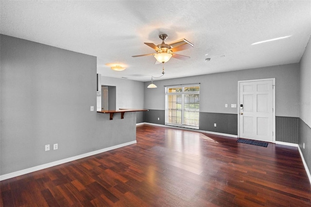 unfurnished living room featuring a textured ceiling, ceiling fan, and dark hardwood / wood-style floors