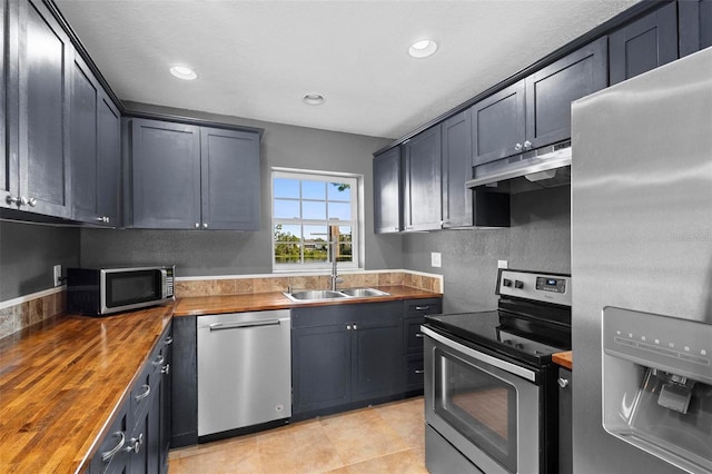 kitchen featuring sink, stainless steel appliances, butcher block counters, and light tile patterned flooring