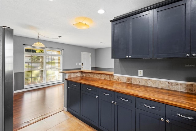 kitchen featuring wooden counters, stainless steel fridge, a textured ceiling, and light hardwood / wood-style floors