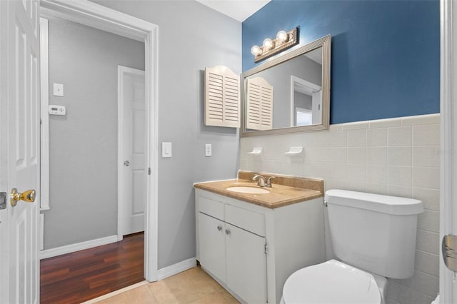 bathroom with hardwood / wood-style floors, vanity, toilet, and tile walls