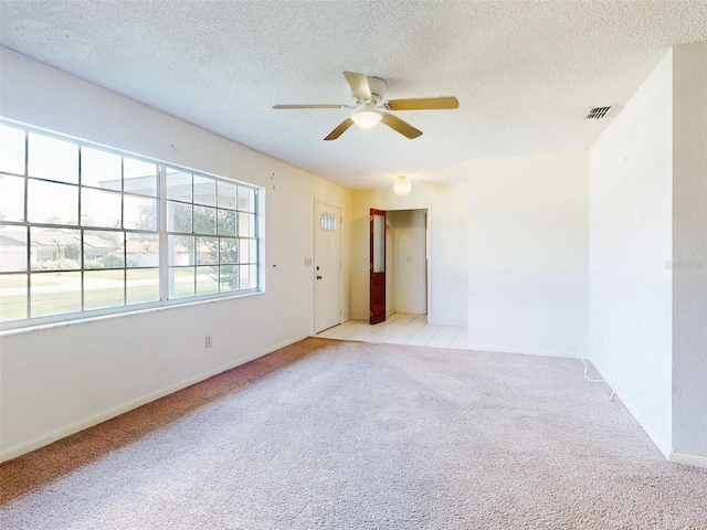 spare room featuring a textured ceiling, light carpet, and ceiling fan