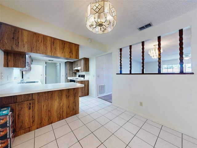 kitchen featuring sink, kitchen peninsula, an inviting chandelier, light tile patterned floors, and decorative light fixtures