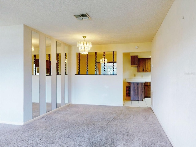 carpeted empty room with a notable chandelier and a textured ceiling