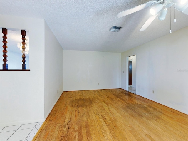 spare room featuring light wood-type flooring, ceiling fan, and a textured ceiling