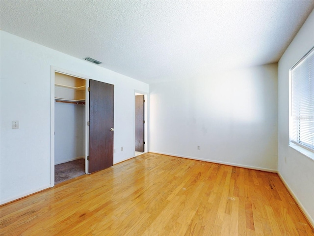 unfurnished bedroom featuring wood-type flooring, a closet, and a textured ceiling