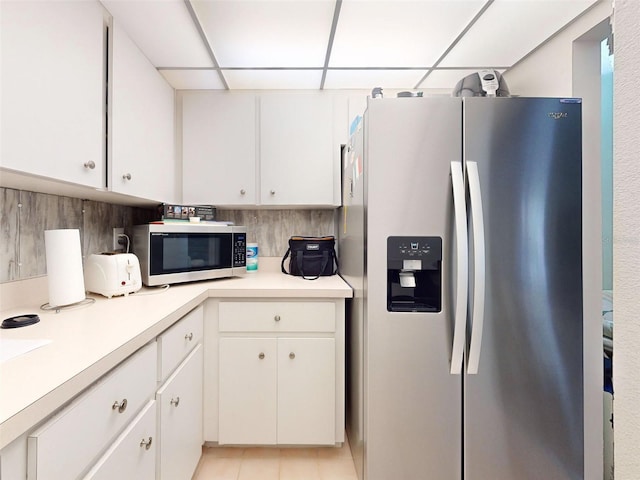 kitchen with backsplash, a drop ceiling, stainless steel appliances, and white cabinets