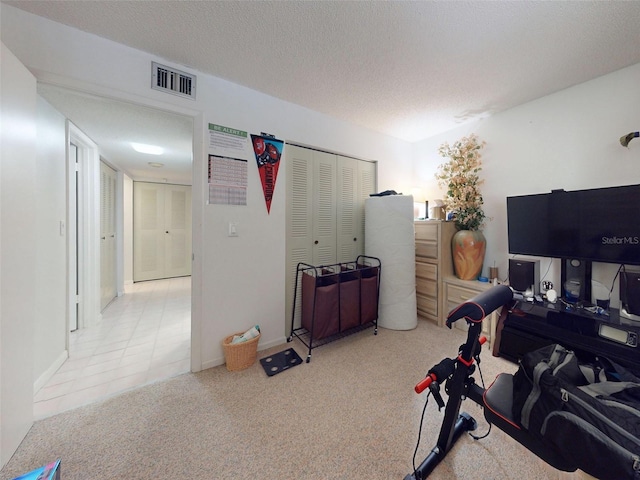 exercise room with a textured ceiling and light tile patterned floors