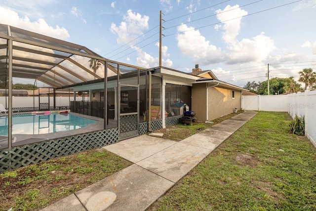 back of property featuring a patio, a yard, a lanai, and a fenced in pool