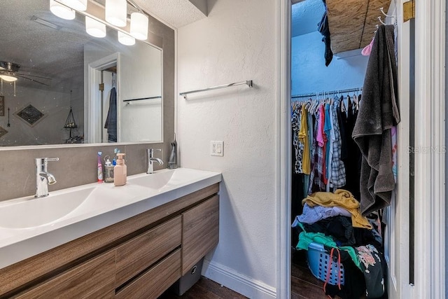 bathroom with a textured ceiling, vanity, walk in shower, and ceiling fan