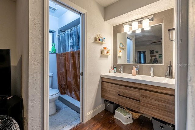 bathroom with hardwood / wood-style floors, a shower with curtain, vanity, and toilet