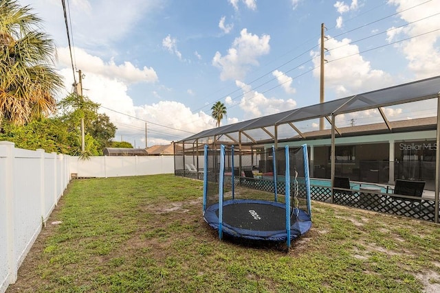 view of yard featuring a trampoline and glass enclosure