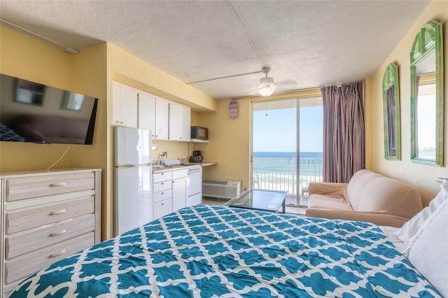 bedroom with white refrigerator, a textured ceiling, access to exterior, and multiple windows