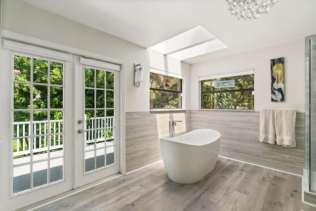 bathroom featuring hardwood / wood-style floors, a skylight, plenty of natural light, and a tub