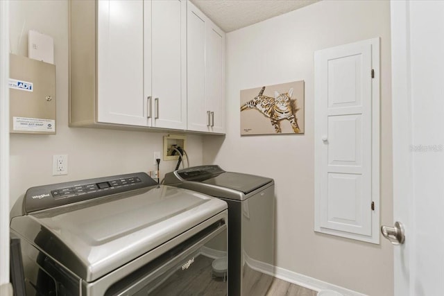 laundry area with cabinets, a textured ceiling, light wood-type flooring, and washer and dryer