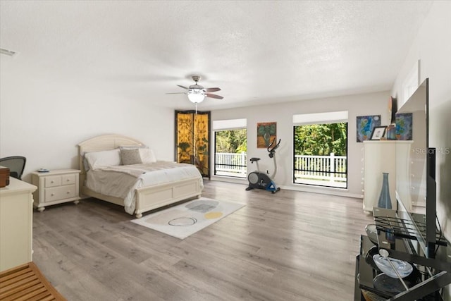 bedroom with ceiling fan, light wood-type flooring, a textured ceiling, and access to outside