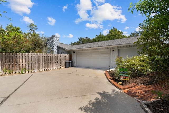 view of side of home featuring a garage, fence, and concrete driveway