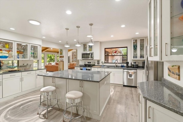 kitchen featuring appliances with stainless steel finishes, a breakfast bar, white cabinets, a kitchen island, and hanging light fixtures