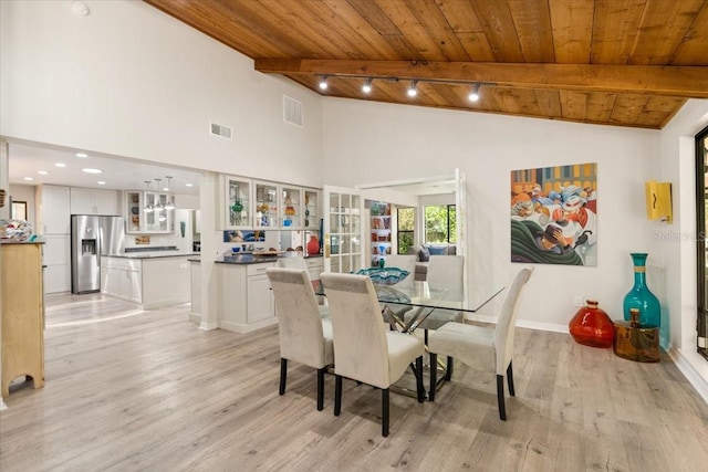 dining room featuring lofted ceiling with beams, light hardwood / wood-style flooring, rail lighting, and wooden ceiling