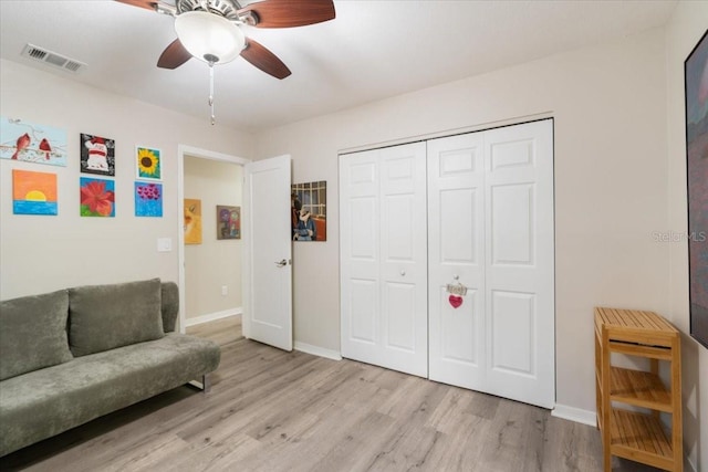 living area with light wood-type flooring, visible vents, ceiling fan, and baseboards