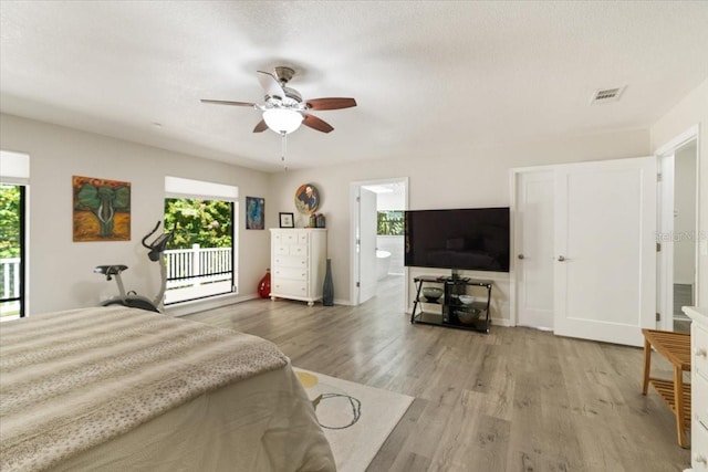 bedroom featuring light wood-style flooring, multiple windows, visible vents, and a textured ceiling