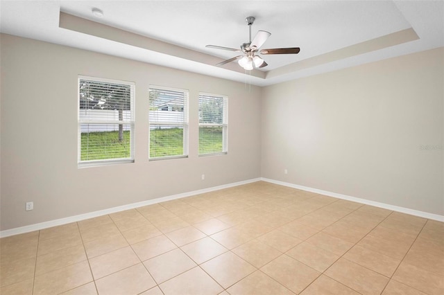 unfurnished room featuring ceiling fan, light tile patterned floors, and a tray ceiling