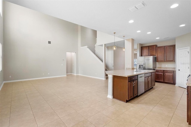 kitchen with light stone counters, light tile patterned floors, an island with sink, appliances with stainless steel finishes, and decorative light fixtures