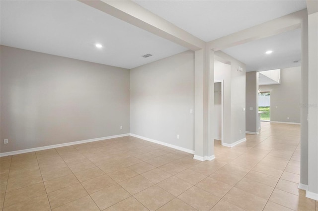 empty room with beamed ceiling and light tile patterned floors