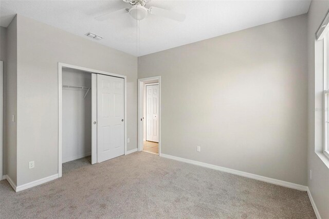 unfurnished bedroom with a closet, light colored carpet, and ceiling fan