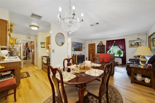 dining area featuring light hardwood / wood-style flooring, a textured ceiling, and sink