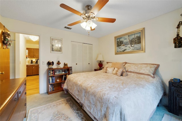 bedroom featuring connected bathroom, light carpet, ceiling fan, and a closet