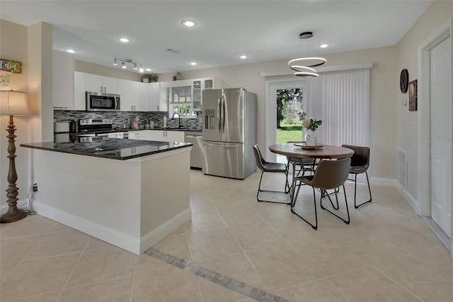 kitchen with appliances with stainless steel finishes, decorative backsplash, white cabinetry, pendant lighting, and sink