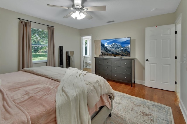 bedroom with light wood-type flooring, ceiling fan, and ensuite bathroom