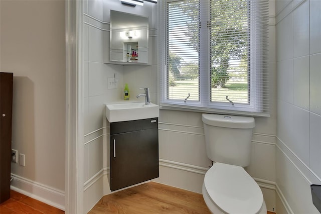 bathroom featuring vanity, tile walls, hardwood / wood-style floors, and toilet