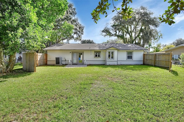 back of house with cooling unit and a yard