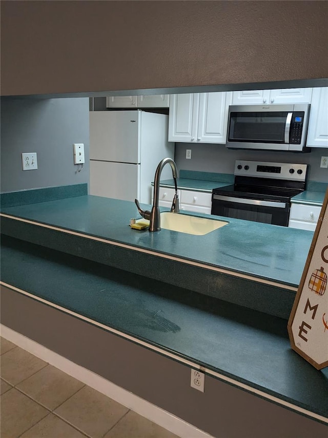 kitchen featuring white cabinets, appliances with stainless steel finishes, tile patterned floors, and sink