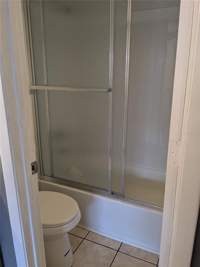 bathroom with ornamental molding, enclosed tub / shower combo, tile patterned floors, and toilet