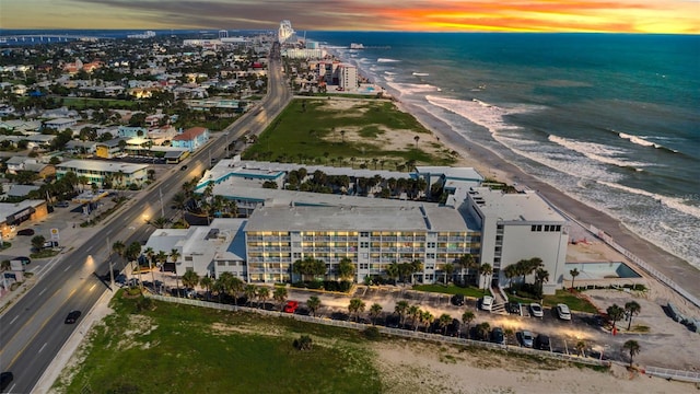 aerial view at dusk with a view of the beach and a water view