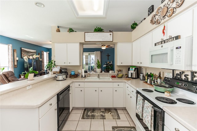 kitchen with sink, kitchen peninsula, light tile patterned floors, white appliances, and white cabinetry