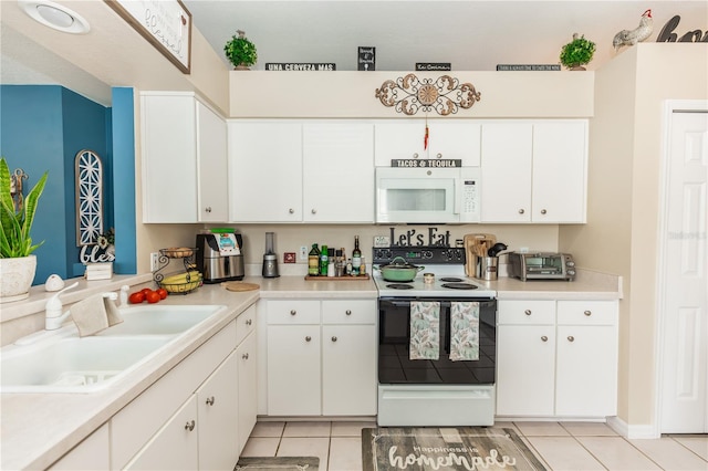 kitchen featuring light tile patterned flooring, sink, white appliances, and white cabinetry