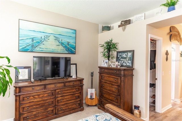 bedroom with a spacious closet, light hardwood / wood-style flooring, and a closet