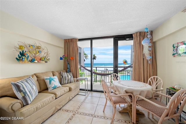 tiled living room featuring a textured ceiling, floor to ceiling windows, and a water view