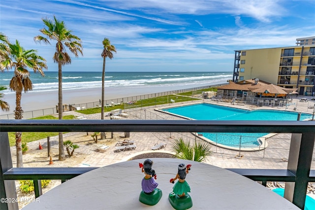 view of pool featuring a patio, a water view, and a beach view