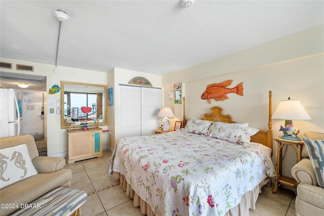 bedroom featuring white fridge, a textured ceiling, and light tile patterned floors