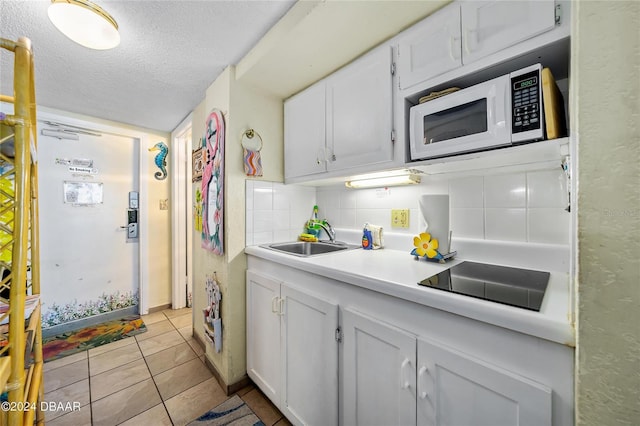 kitchen with a textured ceiling, tasteful backsplash, sink, white cabinets, and black electric cooktop