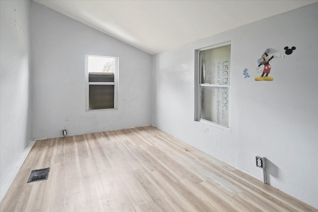 spare room featuring vaulted ceiling and light hardwood / wood-style floors