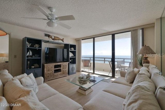 living room featuring expansive windows, a textured ceiling, light wood-type flooring, and ceiling fan