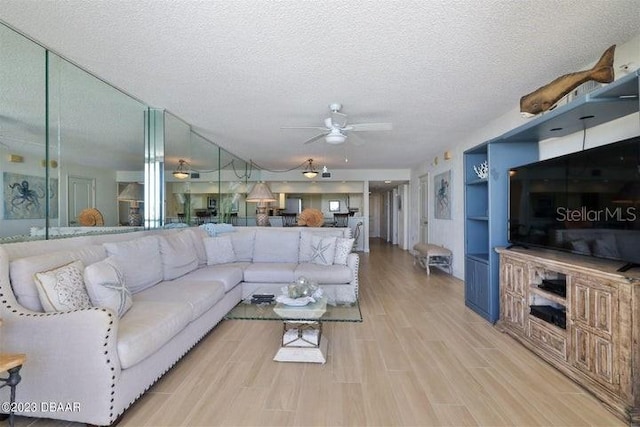 living room featuring light wood-type flooring, a textured ceiling, and ceiling fan